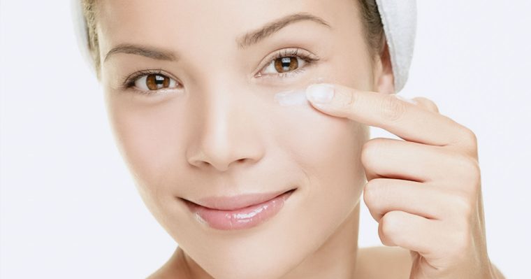 girl applying cream to skin under her eyes