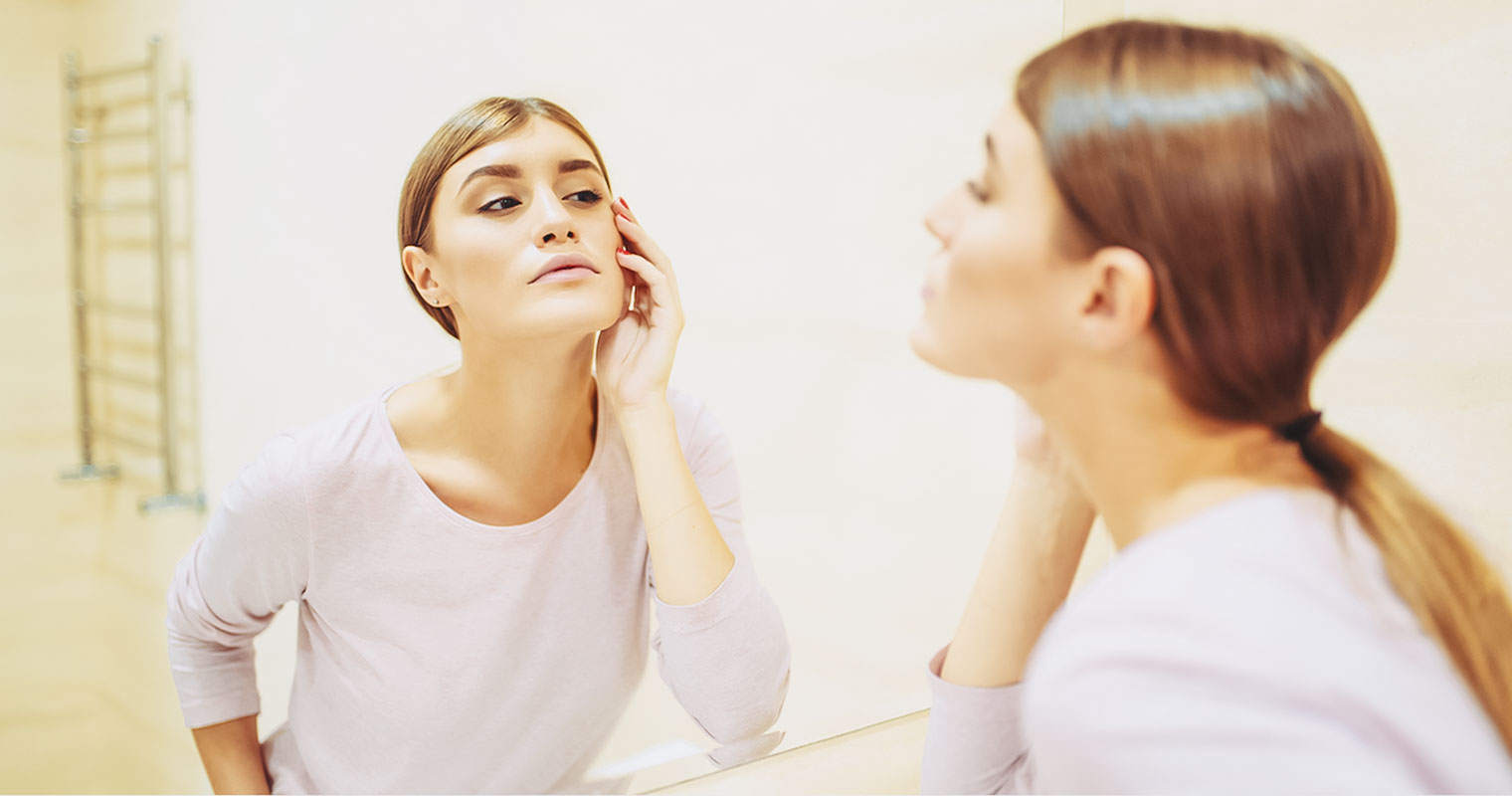 Woman checking her ACNE in a mirror